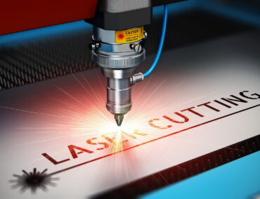 Laser cutting metal industry concept: macro view of industrial digital CNC - computer numerical control CO2 invisible laser beam cutter machine cutting stainless steel sheet with lot of bright shiny sparkles. See also: